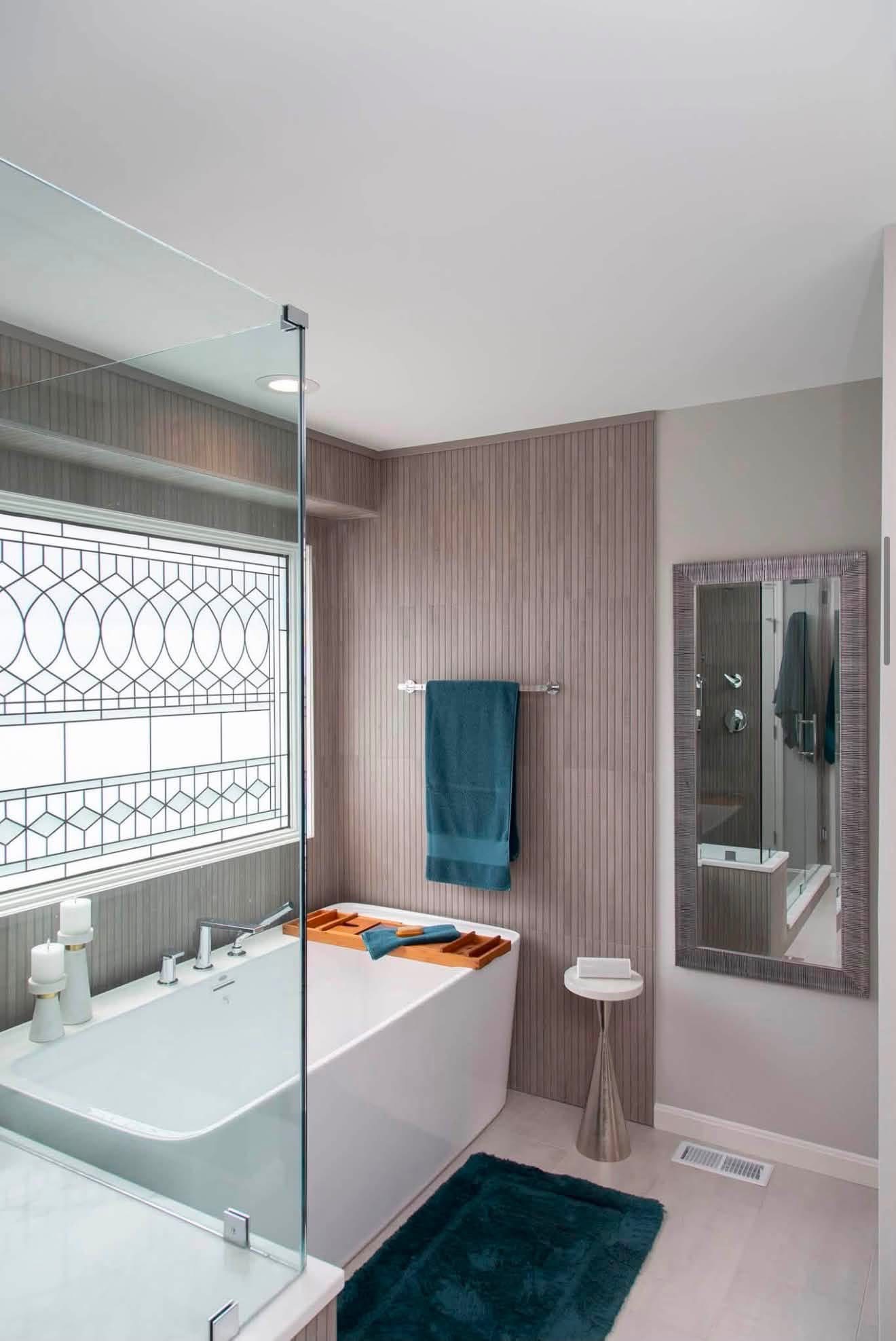 After: freestanding tub by a leaded-glass window with soft textiles and accent mirror